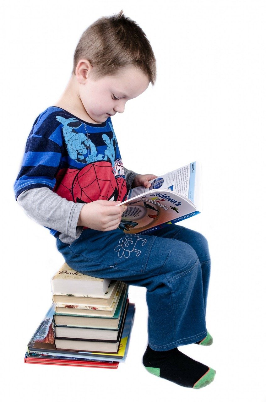 child sitting on a stack of books reading