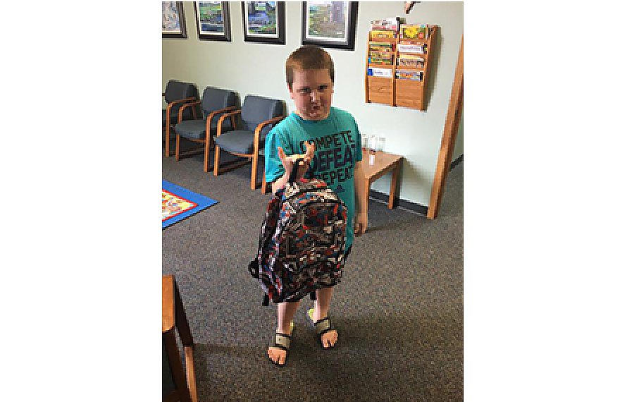 Child showing backpack from giveaway at Comprehensive Rehab