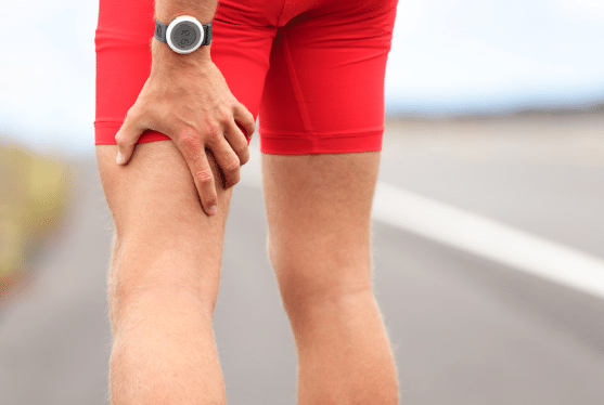 Hand grabbing the back of a leg after a muscle strain.