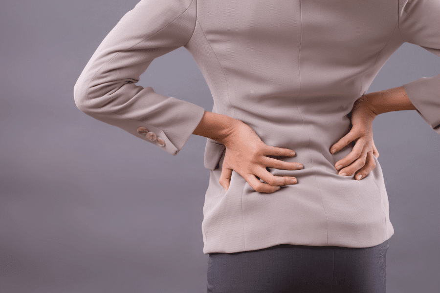 A woman suffering from back pain is holding her back